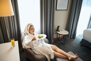 Young Caucasian woman enjoying breakfast in hotel room