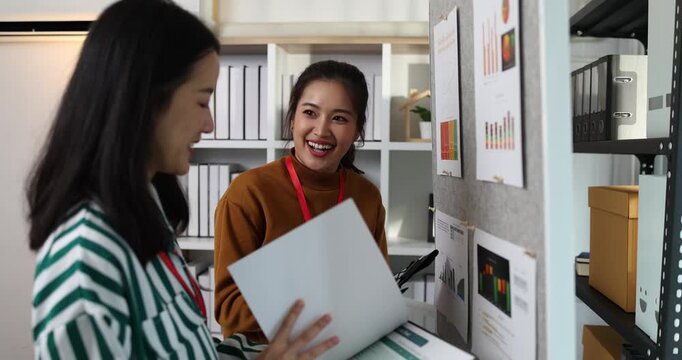 Two businesswomen discussing startup ideas and reviewing documents during a meeting in modern office, representing teamwork, business planning and collaboration in a startup company.
