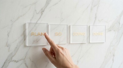 Hand presses a square button on a marble surface with three other buttons beside it.