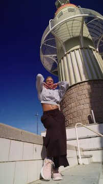 Non binary person vogue dancing on urban stairs with lighthouse