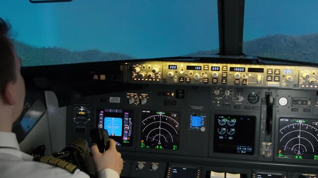 Male pilot in uniform flies airplane with steering wheel pushing thrust lever. Professional captain guides aircraft above mountains