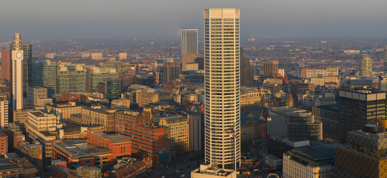 A magnificent golden hour drone shot featuring the unique architecture of the Octagon residential tower, overlooking the dense urban high-rises of Birmingham city centre at sunset.