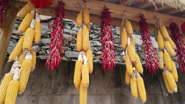 Corn and chili peppers drying under the eaves of a farmhouse