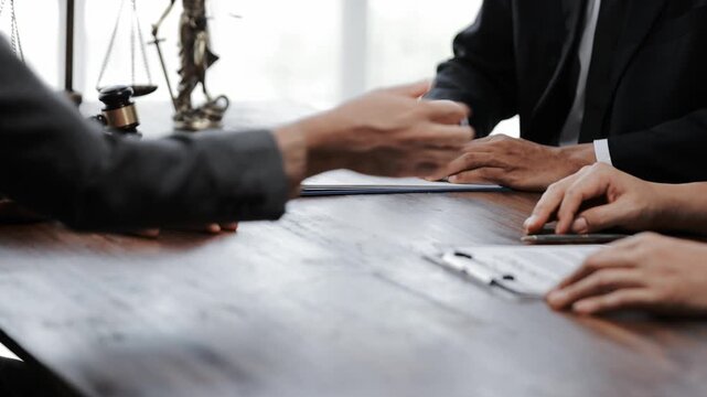 Business people and lawyers having a meeting, signing a contract, and shaking hands to finalize a successful deal in a law firm office