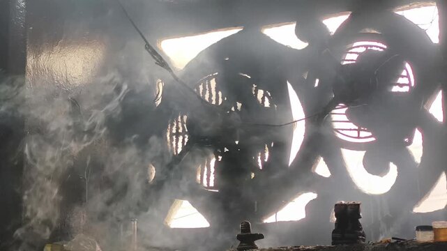 Incense smoke rising inside temple near sacred shrine during Hindu worship ceremony.
