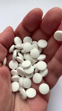 Many pills in the hand. A woman takes a handful of white pills, suicide. Treatment for an illness.