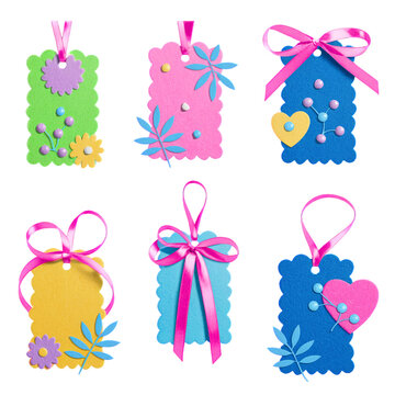 Collection of colorful textured cardstock tags with floral and heart decorations and ribbons
