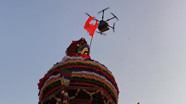 Drone hovering near colorful decorated temple chariot dome during Hindu festival celebration.
