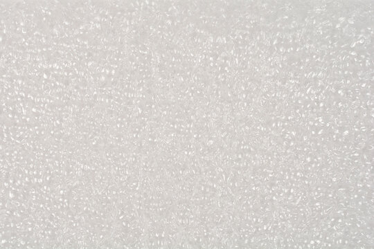 A close up shot of a white expanded polyethylene foam sheet shows its unique cellular structure and textured surface used for protective packaging