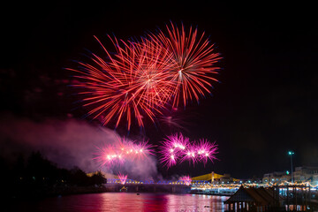 Fototapeta premium Beautiful fireworks display over the river and bridge at night