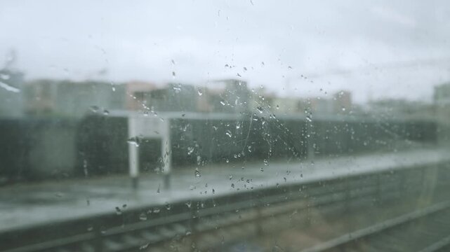 Rain-Streaked Window View of Industrial Train Yard