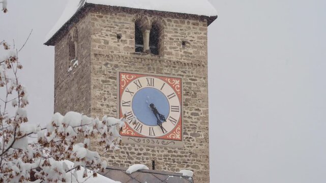 Medieval stone clock tower during a winter snowfall in klosters switzerland