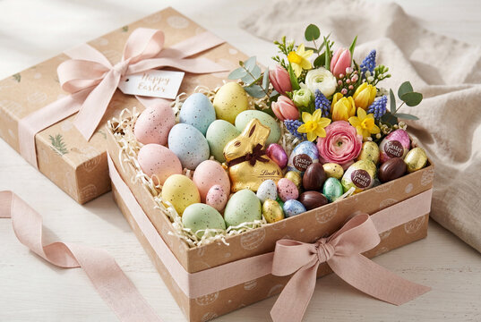 Easter gift box with pastel eggs, chocolate bunny and spring flowers, festive Easter holiday present with decorated eggs, sweets and seasonal spring decoration