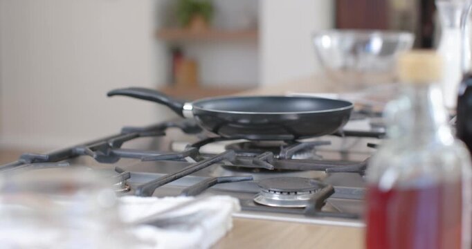 Camera is pulling focus, revealing nonstick frying pan on cooktop for product showcase