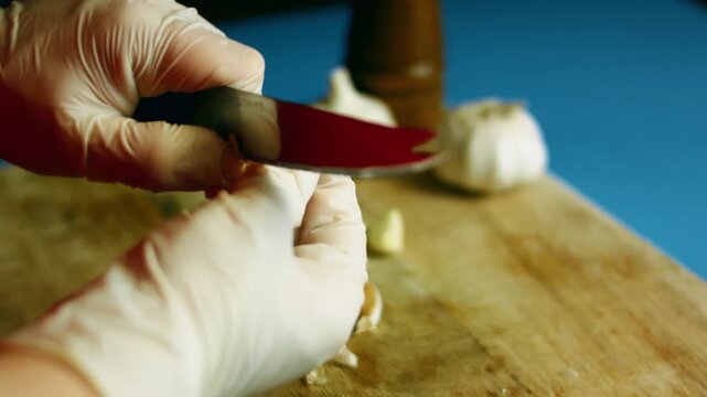 Person wearing gloves peeling cloves from a head of garlic