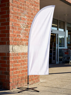 Blank white mockup bow flag standing brick wall sidewalk retail store supermarket outdoor commercial advertising banner template design shopping