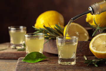 Obraz premium Italian liqueur Limoncello with fresh lemons and rosemary branches.