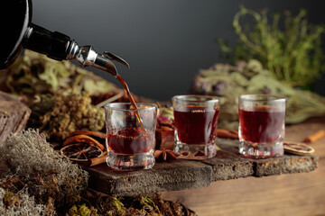 Herbal bitter liqueur is poured from a vintage bottle into a glass.