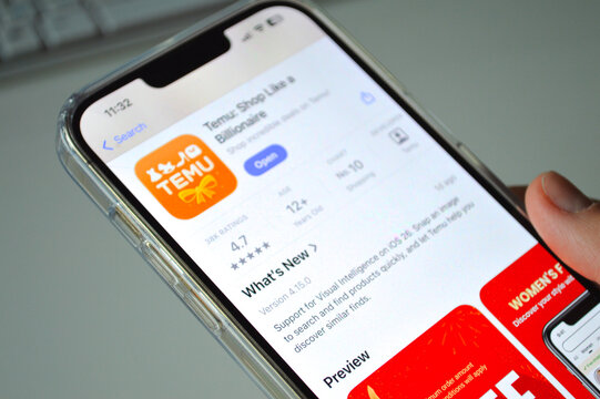 Finger tapping the TEMU app icon on smartphone screen, Polish online shopping concept