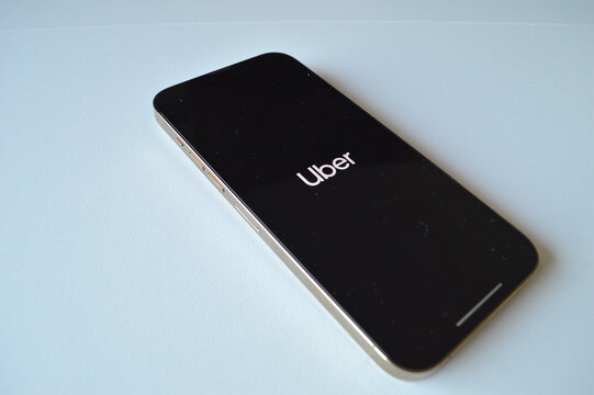 Smartphone lying on a light surface with the Uber app loading screen visible on its black display