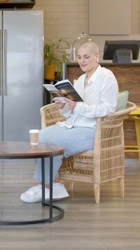 Vertical video: Reading woman in white shirt turning pages to relax at cafe with book and to-go cup