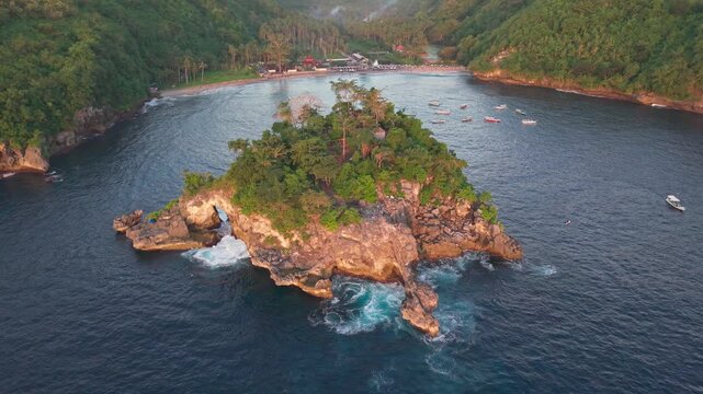 Smooth orbital drone shot of a tropical rocky islet and crashing waves during golden hour