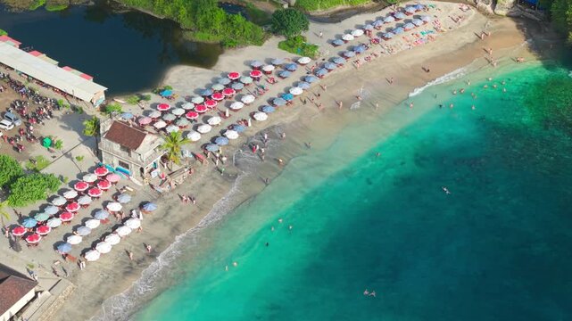 Aerial drone footage of tourists relaxing at Crystal Bay, Nusa Penida on a sunny day