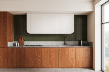 Naklejka premium Modern kitchen interior with wood cabinetry, white upper units and green tiled backsplash in clean contemporary design.