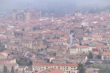 Obraz premium drone viewview of the historic town of Siguenza in Spain covered in thick winter fog featuring the medieval cathedral and traditional tiled roofs under a misty grey sky