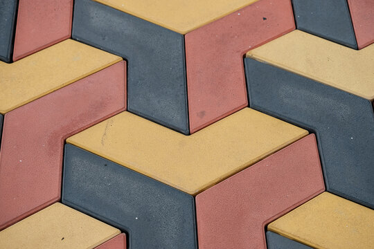 Interlocking zigzag paving blocks in red, yellow, and grey. Concept for Urban geometry, structural durability and modern landscaping design. Interlocking Concrete Pavement (ICP)