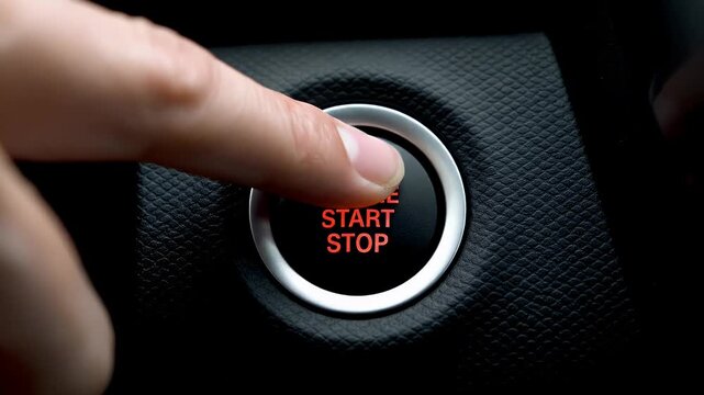 Finger pressing start stop button in car, close-up view, ignition system.