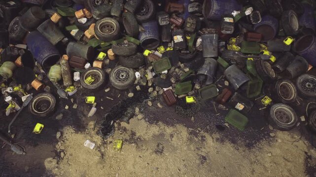Drone view of tires and debris, scattered colorful cardboard and foam pieces on sandy ground creating mosaiclike pattern and pollution visual.