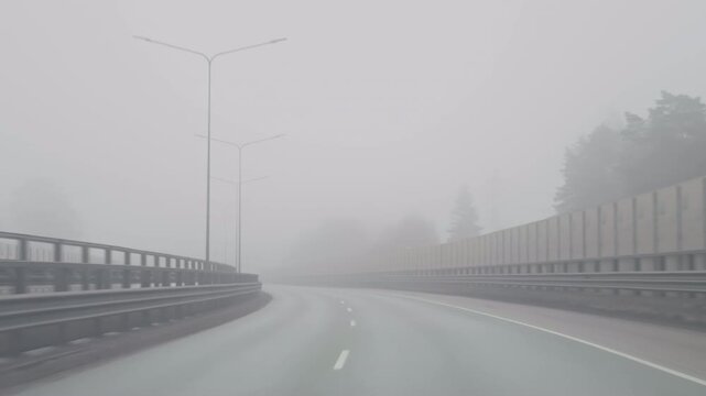 Silent highway with foggy ambiance. Faintly lit road under foggy sky. Urban highway enveloped in mist with subdued lighting and barriers