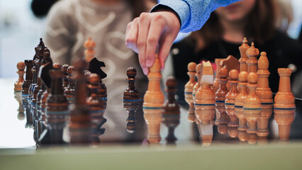 Hand moving a chess piece, reflecting strategy and competition on a board game © Довидович Михаил