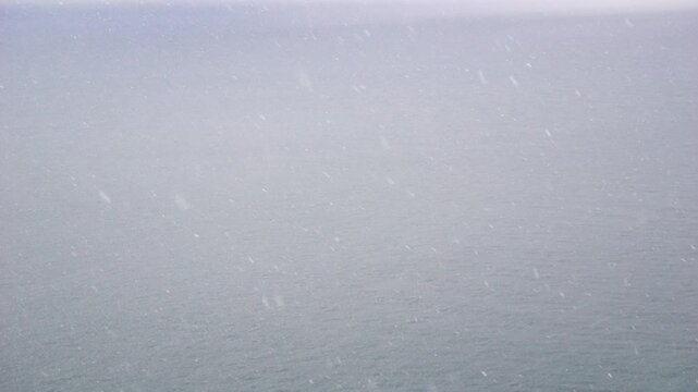 Snowfall Ocean Winter: Aerial view of heavy snowfall over ocean during winter.