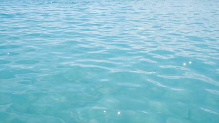 Obraz premium Clear turquoise water surface with sunlight reflections and ripples