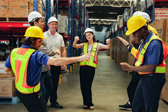 Diverse team male and female workers logistics export warehouse congratulated the outstanding female employees together gave encouragement by dancing having fun everyone admired their talent.