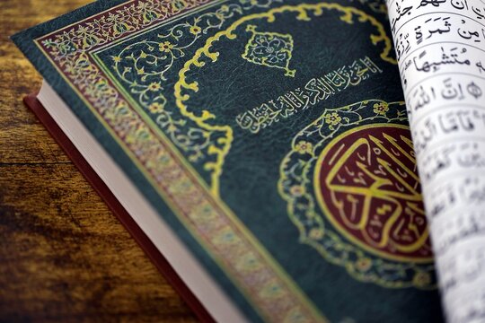 Al Quran Muslim holy book on table in mosque. Details of arabic calligraphy on islamic book cover close up. Concept of Islam religion and praying in arabic countries