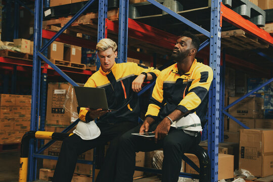 Two male workers responsible checking inventory warehouse are bored with their job both them feeling burnt out from their regular work feeling bored unhappy work sitting around with their minds blank.