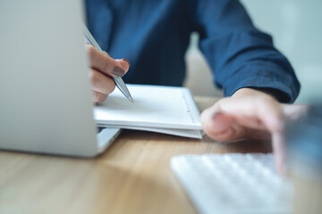 Fototapeta premium Close up business woman working, using calculator to calculate budget and tax with laptop on office desk, budget management and tax calculation.