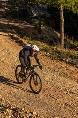 Male cyclist enjoying an off-road adventure, riding a gravel bike on a rocky mountain path under the warm sun in the costa blanca region of Spain, engaging in intense outdoor sport - stock photo
