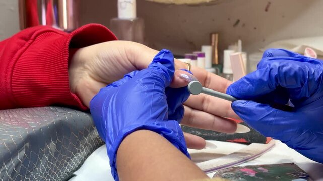 Nail technician creating cat eye magnetic effect on nails using special magnet tool and gel polish during manicure session in modern beauty salon.