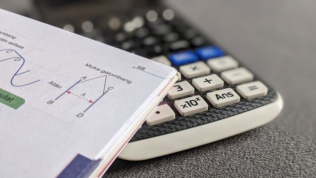 Scientific Calculator and Physics Textbook on Student Desk