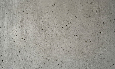 Fototapeta premium Concrete surface displays a textured pattern with visible imperfections and small black specks. The neutral gray color provides a versatile backdrop suitable for various designs.