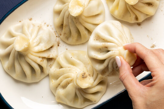 Charming khinkali dumplings gently cradled by a fair-skinned woman, capturing flavors of Georgian Supra and Lunar New Year feasts