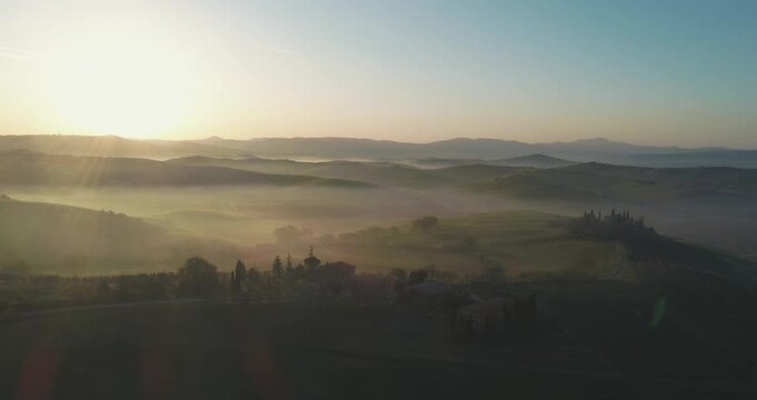 Classic Tuscany landscape with green hills and farmland country at sunrise. Aerial shot of green spring fields and hills in Tuscany, Italy
