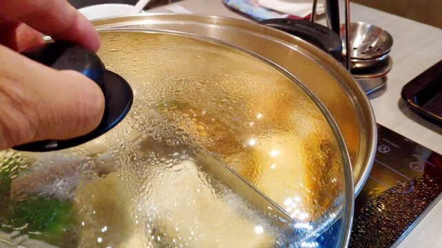 Fresh ingredients and sausages simmering in a steaming Japanese hot pot at an authentic restaurant table