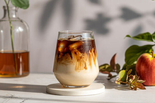 Refreshing iced coffee with milk swirl in glass on white coaster isolated on transparent background