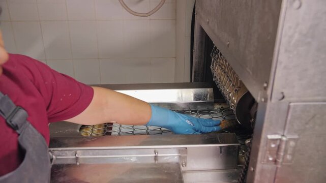 Worker Feeding Fish Into Industrial Cutting Conveyor Machine