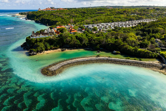 Drone shot of stunning Nusa Dua coastline showing coral reef, resort villas and lush trees
